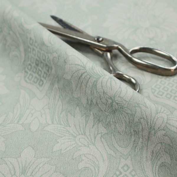 Elegant pale grey damask fabric featuring a large-scale, repeating floral medallion pattern in shimmering silvery-white tones.