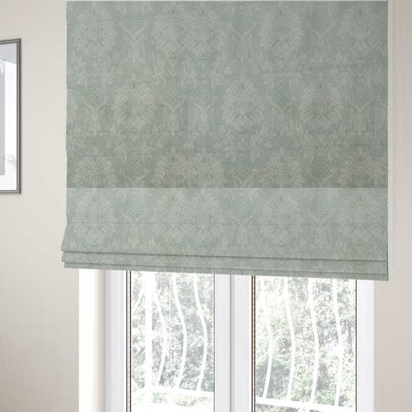 The fabric used to create these Roman blinds is a elegant pale grey damask fabric featuring a large-scale, repeating floral medallion pattern in shimmering silvery-white tones.