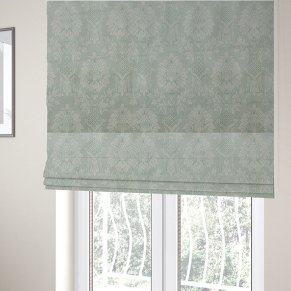 The fabric used to create these Roman blinds is a elegant pale grey damask fabric featuring a large-scale, repeating floral medallion pattern in shimmering silvery-white tones.