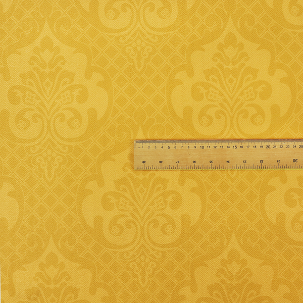 A vibrant yellow damask fabric featuring a tonal, monochrome design. Ornate, stylized floral medallions and acanthus leaves are woven in a slightly lighter shade of yellow, creating a subtle shimmer. The pattern is set against a background of a fine diagonal lattice grid, with a visible woven texture throughout the material.