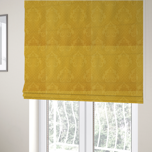 The fabric used to create these Roman blinds is a vibrant yellow damask fabric featuring a tonal, monochrome design. Ornate, stylized floral medallions and acanthus leaves are woven in a slightly lighter shade of yellow, creating a subtle shimmer. The pattern is set against a background of a fine diagonal lattice grid, with a visible woven texture throughout the material.