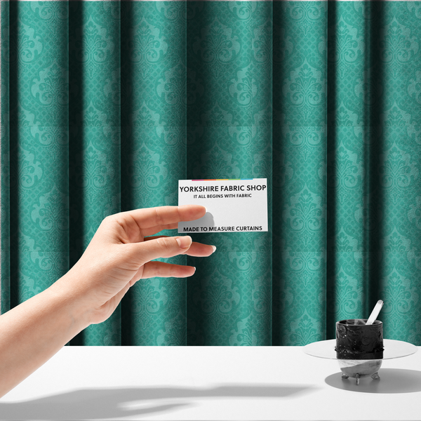 The fabric used to create these made-to-measure curtains has a design that features large, ornate floral medallions and scrolling acanthus leaves in a bright turquoise shade, set against a slightly lighter mint green background. A fine diagonal lattice grid fills the background between the motifs, and the material shows a clear woven texture that provides visual depth to the tonal design.