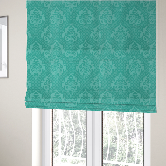 The fabric used to create these Roman blinds has a design that features large, ornate floral medallions and scrolling acanthus leaves in a bright turquoise shade, set against a slightly lighter mint green background. A fine diagonal lattice grid fills the background between the motifs, and the material shows a clear woven texture that provides visual depth to the tonal design.