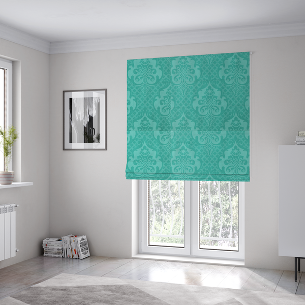The fabric used to create these Roman blinds has a design that features large, ornate floral medallions and scrolling acanthus leaves in a bright turquoise shade, set against a slightly lighter mint green background. A fine diagonal lattice grid fills the background between the motifs, and the material shows a clear woven texture that provides visual depth to the tonal design.