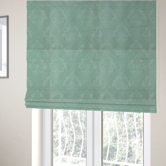 The fabric used to create these Roman blinds has a design that consists of large, ornate floral medallions and scrolling acanthus leaves woven in a shade very close to the background colour, creating a delicate, shimmering effect. A fine diagonal lattice grid fills the background between the motifs, and the material displays a clear woven texture throughout.