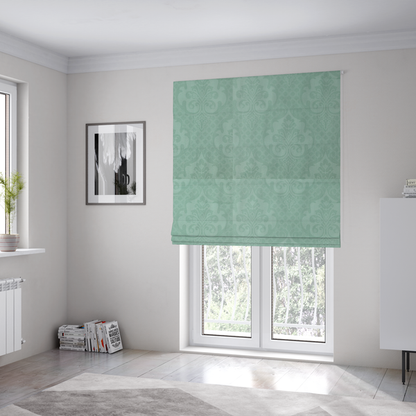 The fabric used to create these Roman blinds has a design that consists of large, ornate floral medallions and scrolling acanthus leaves woven in a shade very close to the background colour, creating a delicate, shimmering effect. A fine diagonal lattice grid fills the background between the motifs, and the material displays a clear woven texture throughout.
