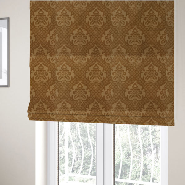 The fabric used to create these Roman blinds has a design that features large, ornate floral medallions and scrolling acanthus leaves in a warm tan shade, set against a rich golden-brown background. A fine diagonal lattice grid creates a diamond pattern in the negative space between the motifs, and the material displays a clear woven texture that adds depth and a subtle sheen to the pattern.