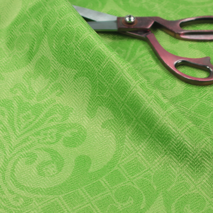 The design features large, ornate floral medallions and scrolling acanthus leaves in a vibrant lime shade, set against a slightly lighter green background. A fine diagonal lattice grid fills the background between the motifs, and the material shows a clear woven texture that provides visual depth to the tonal design.