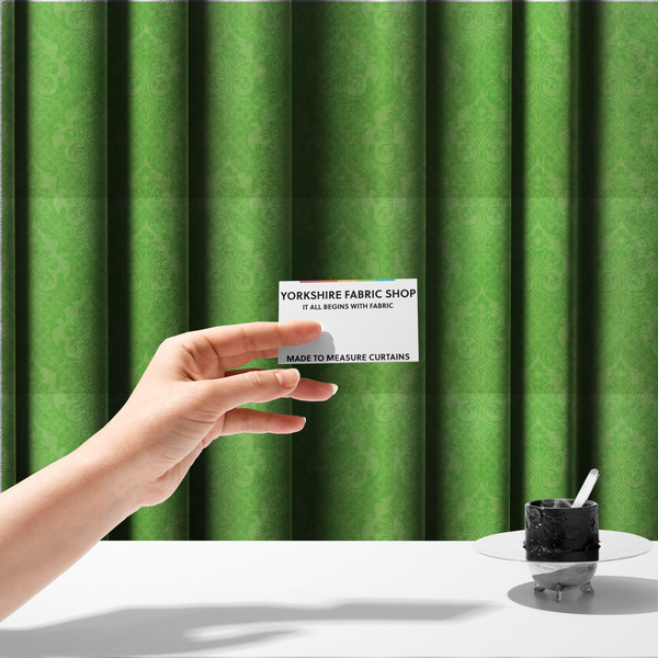 The fabric used to create these made-to-measure curtains has a design that features large, ornate floral medallions and scrolling acanthus leaves in a vibrant lime shade, set against a slightly lighter green background. A fine diagonal lattice grid fills the background between the motifs, and the material shows a clear woven texture that provides visual depth to the tonal design.