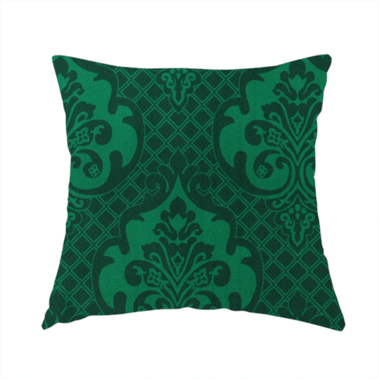 The fabric used to create this handmade cushion has a design that showcases large, ornate floral medallions and scrolling acanthus leaves in a vibrant green hue, set against a darker, forest green background. A fine diagonal lattice grid creates a diamond pattern in the spaces between the motifs, and the material displays a distinct woven texture that adds depth and classic character to the design.