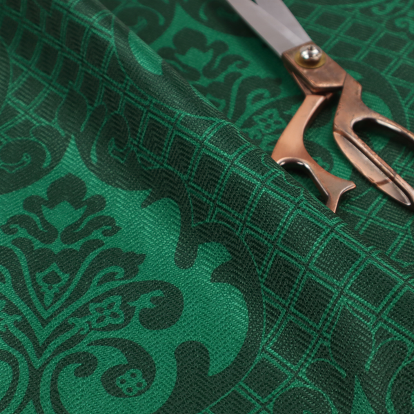 The design showcases large, ornate floral medallions and scrolling acanthus leaves in a vibrant green hue, set against a darker, forest green background. A fine diagonal lattice grid creates a diamond pattern in the spaces between the motifs, and the material displays a distinct woven texture that adds depth and classic character to the design.