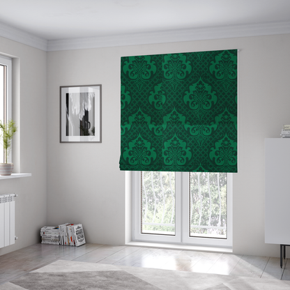 The fabric used to create these Roman blinds has a design that showcases large, ornate floral medallions and scrolling acanthus leaves in a vibrant green hue, set against a darker, forest green background. A fine diagonal lattice grid creates a diamond pattern in the spaces between the motifs, and the material displays a distinct woven texture that adds depth and classic character to the design.