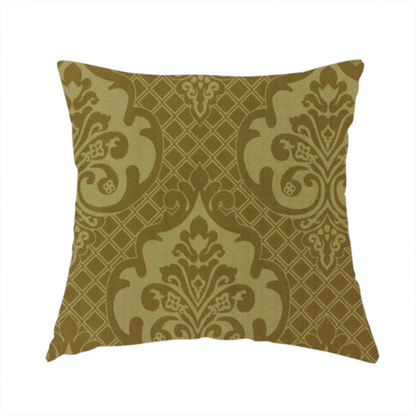 The fabric used to create this handmade cushion is a design that showcases large, ornate floral medallions and scrolling acanthus leaves in a muted tan shade, set against a rich ochre background. A fine diagonal lattice grid creates a diamond pattern in the spaces between the motifs, and the material displays a clear woven texture that adds depth and a subtle sheen to the pattern.