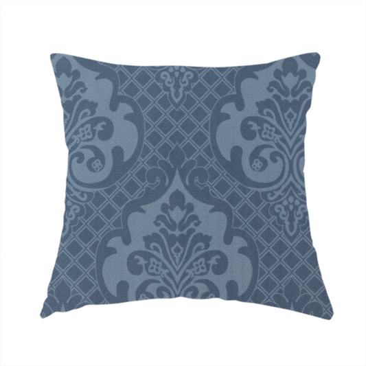 The fabric used to create this handmade cushion has a dusty blue and steel grey damask pattern on a textured fabric. Large, ornate floral motifs with stylized acanthus leaves are arranged in a repeating grid. These medallions are a lighter, cool-toned blue-grey set against a darker navy-blue background.