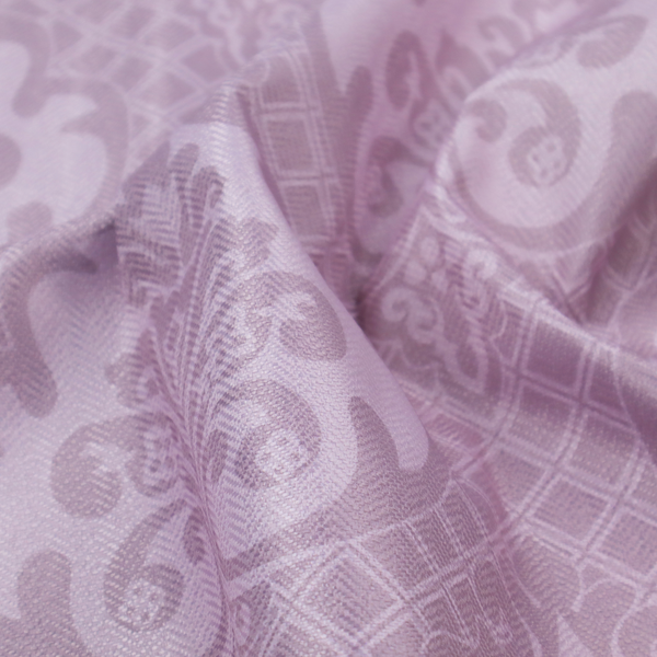 The design features large, ornate floral medallions and scrolling acanthus leaves in a light lavender shade, set against a slightly darker mauve background. A fine diagonal lattice grid fills the background between the motifs, and the material shows a clear woven texture that provides visual depth to the tonal design.