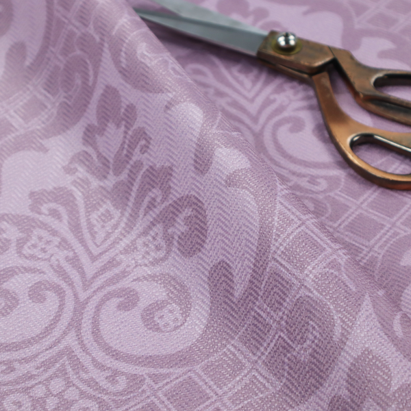 The design features large, ornate floral medallions and scrolling acanthus leaves in a light lavender shade, set against a slightly darker mauve background. A fine diagonal lattice grid fills the background between the motifs, and the material shows a clear woven texture that provides visual depth to the tonal design.