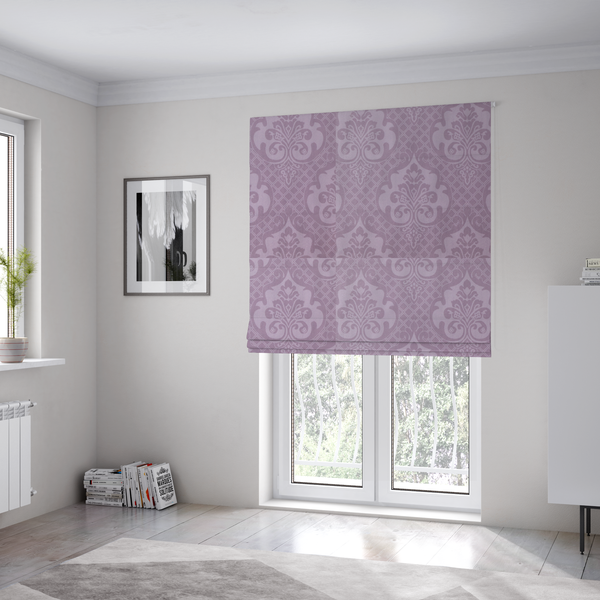 The fabric used to create these Roman blinds has a design that features large, ornate floral medallions and scrolling acanthus leaves in a light lavender shade, set against a slightly darker mauve background. A fine diagonal lattice grid fills the background between the motifs, and the material shows a clear woven texture that provides visual depth to the tonal design.