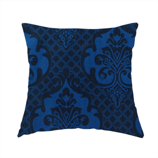 The fabric used to create this handmade cushion has a design that features large, ornate floral medallions and scrolling acanthus leaves in a bright royal blue shade, set against a deep navy background. A fine diagonal lattice grid fills the space between the motifs, and the material displays a clear woven texture that adds structural depth and a subtle sheen to the tonal blue design.