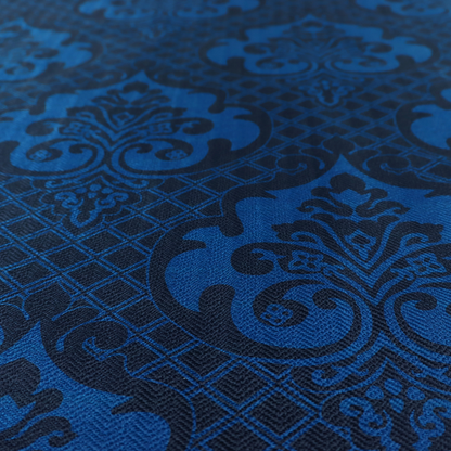 The design features large, ornate floral medallions and scrolling acanthus leaves in a bright royal blue shade, set against a deep navy background. A fine diagonal lattice grid fills the space between the motifs, and the material displays a clear woven texture that adds structural depth and a subtle sheen to the tonal blue design.