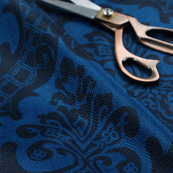 The design features large, ornate floral medallions and scrolling acanthus leaves in a bright royal blue shade, set against a deep navy background. A fine diagonal lattice grid fills the space between the motifs, and the material displays a clear woven texture that adds structural depth and a subtle sheen to the tonal blue design.