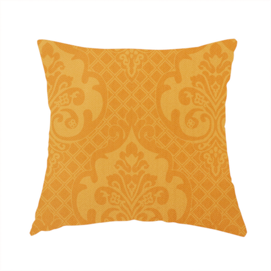 The fabric used to create this handmade cushion has an orange damask pattern on a textured fabric. Large, ornate floral motifs and scrolling acanthus leaves are arranged in a repeating grid. These motifs are rendered in a soft peach shade against a more saturated, vibrant orange background.