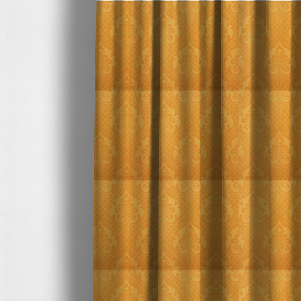 The fabric used to create these made-to-measure curtains has an orange damask pattern on a textured fabric. Large, ornate floral motifs and scrolling acanthus leaves are arranged in a repeating grid. These motifs are rendered in a soft peach shade against a more saturated, vibrant orange background.