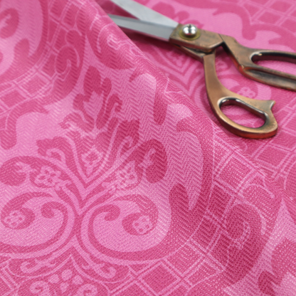 The design features large, ornate floral medallions and scrolling acanthus leaves in a lighter pink shade, set against a saturated magenta-rose background. A fine diagonal lattice grid fills the background between the motifs, and the material shows a clear woven texture that provides visual depth to the traditional design.