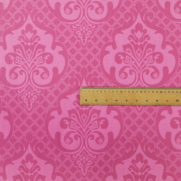 The design features large, ornate floral medallions and scrolling acanthus leaves in a lighter pink shade, set against a saturated magenta-rose background. A fine diagonal lattice grid fills the background between the motifs, and the material shows a clear woven texture that provides visual depth to the traditional design.
