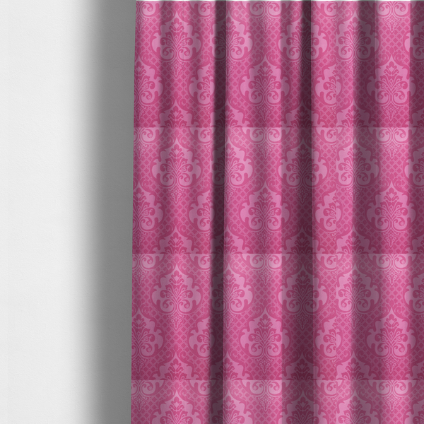 The fabric used to create these made-to-measure curtains has a design that features large, ornate floral medallions and scrolling acanthus leaves in a lighter pink shade, set against a saturated magenta-rose background. A fine diagonal lattice grid fills the background between the motifs, and the material shows a clear woven texture that provides visual depth to the traditional design.