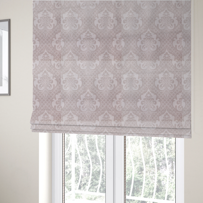 The fabric used to create these Roman blinds has a baby pink and cream damask pattern on a textured fabric. The design features large, ornate floral medallions with stylized acanthus leaf scrolls, arranged in a structured, repeating grid.