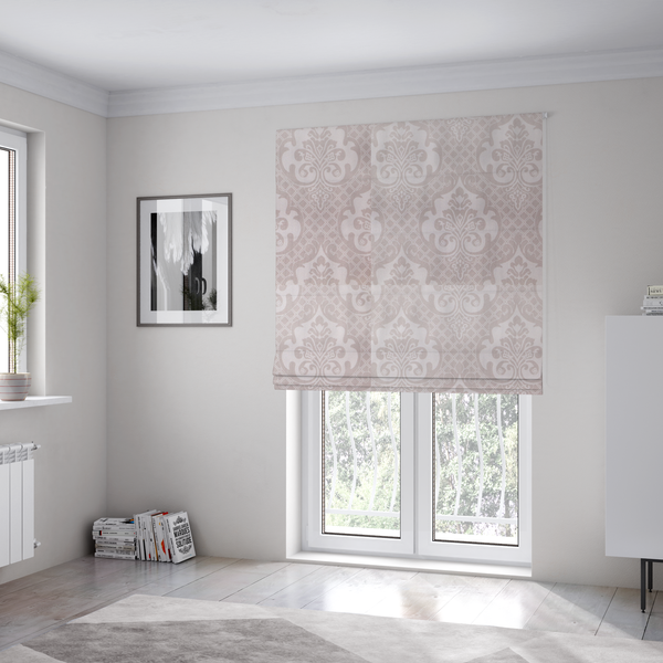 The fabric used to create these Roman blinds has a baby pink and cream damask pattern on a textured fabric. The design features large, ornate floral medallions with stylized acanthus leaf scrolls, arranged in a structured, repeating grid.