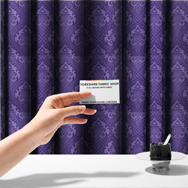 The fabric used to create these made-to-measure curtains has a design that features large, ornate floral medallions and scrolling acanthus leaves in a lighter violet shade, set against a deep, saturated purple background. A fine diagonal lattice grid fills the background between the motifs, and the material displays a clear woven texture that adds structural depth and a sophisticated sheen to the tonal design.