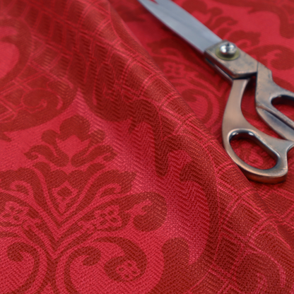 The design features large, ornate floral medallions and scrolling acanthus leaves in a slightly lighter shade of red, creating a tonal, high-contrast effect. A fine diagonal lattice grid fills the background between the motifs, and the material shows a clear woven texture that adds depth and a traditional feel to the design.