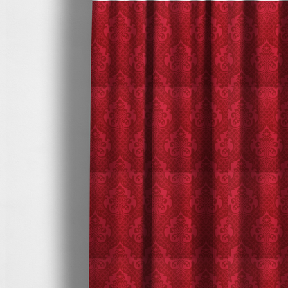 The fabric used to create these made-to-measure curtains has a design that features large, ornate floral medallions and scrolling acanthus leaves in a slightly lighter shade of red, creating a tonal, high-contrast effect. A fine diagonal lattice grid fills the background between the motifs, and the material shows a clear woven texture that adds depth and a traditional feel to the design.