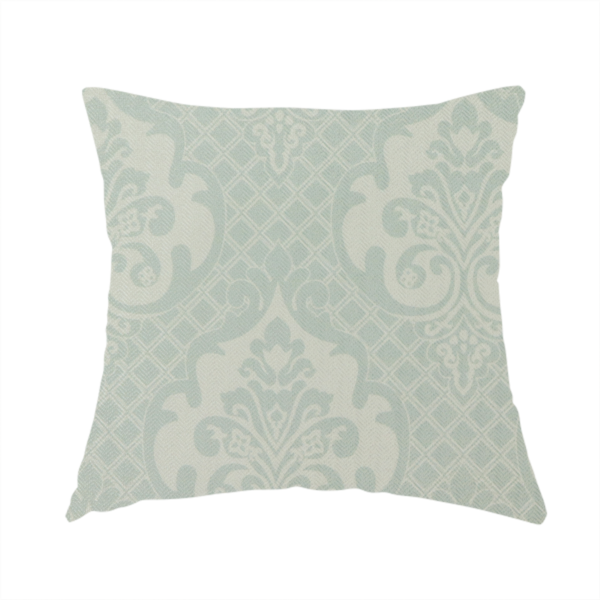 The fabric used to create this handmade cushion has a design that showcases large, ornate floral medallions and scrolling acanthus leaves in a light silver shade, set against a slightly darker grey-white background. A fine diagonal lattice grid creates a diamond pattern in the negative space between the motifs, and the material displays a clear woven texture that adds a sophisticated, metallic-like shimmer to the pattern.