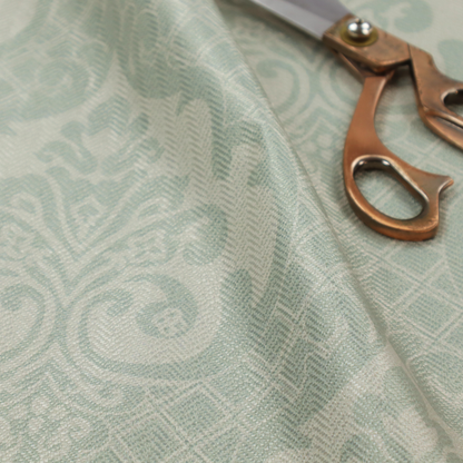 The design showcases large, ornate floral medallions and scrolling acanthus leaves in a light silver shade, set against a slightly darker grey-white background. A fine diagonal lattice grid creates a diamond pattern in the negative space between the motifs, and the material displays a clear woven texture that adds a sophisticated, metallic-like shimmer to the pattern.