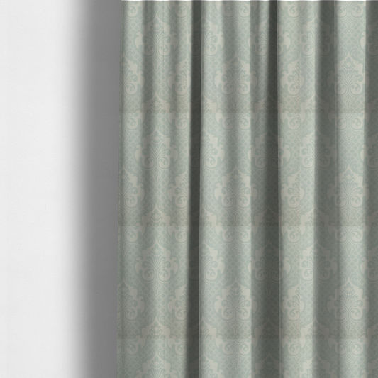 The fabric used to create these made-to-measure curtains has a design that showcases large, ornate floral medallions and scrolling acanthus leaves in a light silver shade, set against a slightly darker grey-white background. A fine diagonal lattice grid creates a diamond pattern in the negative space between the motifs, and the material displays a clear woven texture that adds a sophisticated, metallic-like shimmer to the pattern.