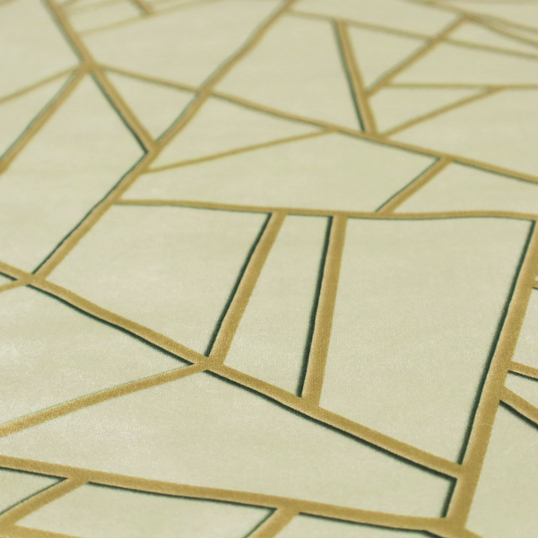 A close-up of a luxurious fabric featuring a geometric, fractured glass pattern. The design consists of irregular, sharp-angled polygons in a pale sage green or muted seafoam hue. These shapes are separated by thick, shimmering gold metallic lines that appear slightly recessed or embossed, creating a high-contrast, mosaic-like effect.