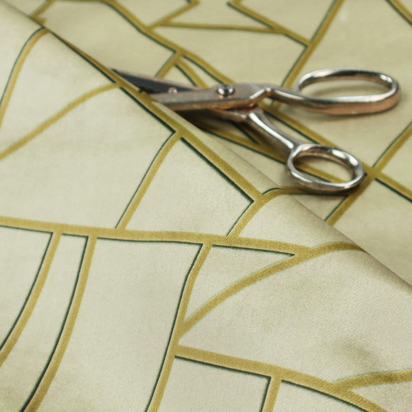 A close-up of a luxurious fabric featuring a geometric, fractured glass pattern. The design consists of irregular, sharp-angled polygons in a pale sage green or muted seafoam hue. These shapes are separated by thick, shimmering gold metallic lines that appear slightly recessed or embossed, creating a high-contrast, mosaic-like effect.