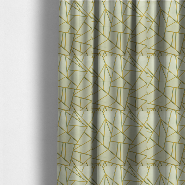 The fabric used to create these made-to-measure curtains, features a geometric, fractured glass pattern. The design consists of irregular, sharp-angled polygons in a pale sage green or muted seafoam hue. These shapes are separated by thick, shimmering gold metallic lines that appear slightly recessed or embossed, creating a high-contrast, mosaic-like effect.