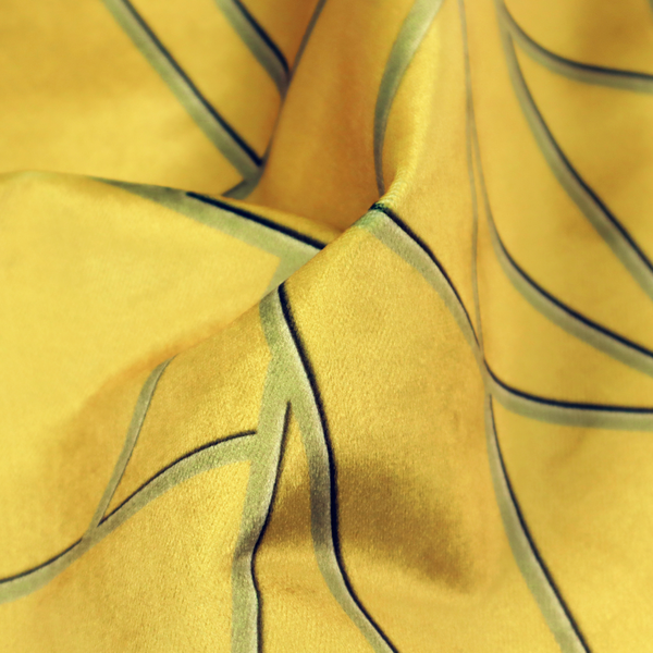 A close-up of a luxurious mustard yellow fabric featuring a bold geometric, fractured pattern. The design is composed of sharp, irregular polygons separated by embossed tone-on-tone lines in a slightly darker, olive-tinted gold.