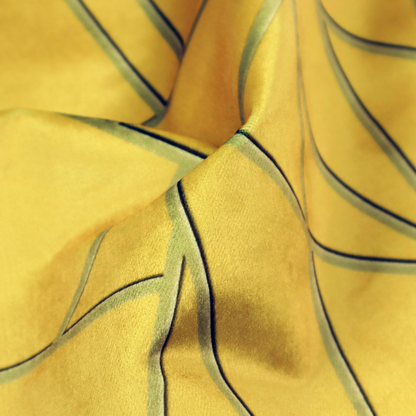 A close-up of a luxurious mustard yellow fabric featuring a bold geometric, fractured pattern. The design is composed of sharp, irregular polygons separated by embossed tone-on-tone lines in a slightly darker, olive-tinted gold.