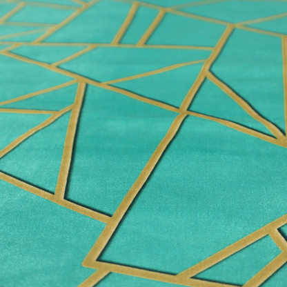 A close-up of a luxurious teal or bright turquoise fabric featuring a fractured, geometric mosaic pattern. The vibrant, plush background is divided by a network of shimmering metallic gold lines that form sharp, irregular polygons. The design creates a striking shattered-glass or "cracked ice" effect, blending a high-energy jewel tone with sophisticated, Art Deco-inspired gold linework for a modern, architectural look.