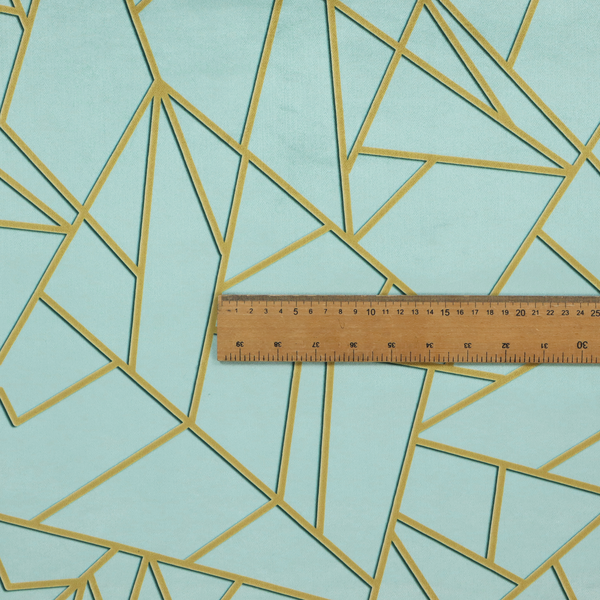 A close-up of a luxurious light aqua or pale sky blue fabric featuring a fractured, geometric mosaic pattern. The soft, matte background is segmented by a network of embossed metallic gold lines that create sharp, irregular polygons. This "cracked ice" or shattered-glass effect pairs a serene, cool-toned pastel with warm, shimmering gold linework for a sophisticated and modern Art Deco-inspired look.