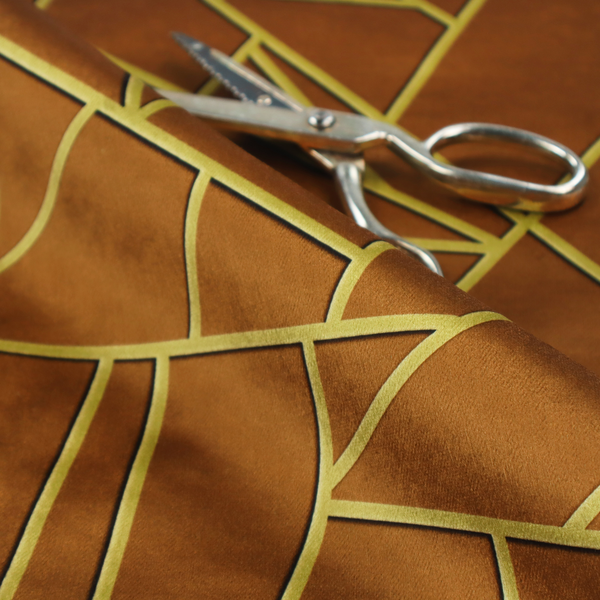 A close-up of a luxurious brown or rust-coloured fabric featuring a fractured, geometric mosaic pattern. The warm, matte background is divided by a network of recessed gold metallic lines that form sharp, irregular polygons. This "cracked ice" or shattered-glass effect creates a bold, architectural look, blending the deep, earthy tones of the textile with shimmering, Art Deco-inspired accents.