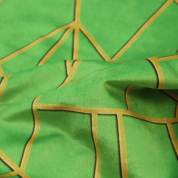 A close-up of a vibrant bright green fabric featuring a fractured, geometric mosaic pattern. The lively, matte background is segmented by a network of recessed metallic gold lines that form sharp, irregular polygons. This "cracked ice" or shattered-glass effect creates a bold, modern look, combining a lush, verdant base with shimmering, Art Deco-inspired accents.