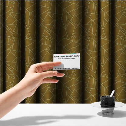 The fabric used to create these made-to-measure curtains is a luxurious olive gold or antique brass-coloured fabric featuring a fractured, geometric mosaic pattern. The rich, matte background is segmented by a network of recessed tone-on-tone lines in a slightly lighter, shimmering shade. This "cracked ice" or shattered-glass effect creates a subtle, sophisticated 3D texture, blending mid-century modern influence with contemporary Art Deco elegance.