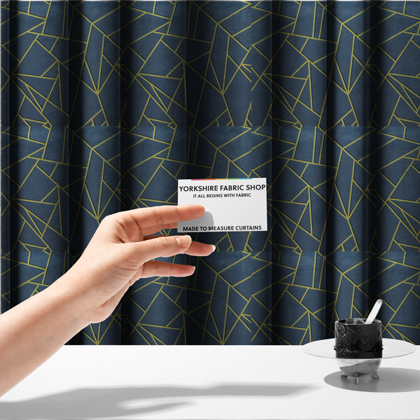 The fabric used to create these made-to-measure curtains is a luxurious slate grey fabric featuring a fractured, geometric mosaic pattern. The deep, matte background is segmented by a network of recessed metallic gold lines that form sharp, irregular polygons. This "shattered-glass" effect creates a striking visual contrast, blending the cool, dark tones of the textile with shimmering, Art Deco-inspired accents for a modern, high-end look.