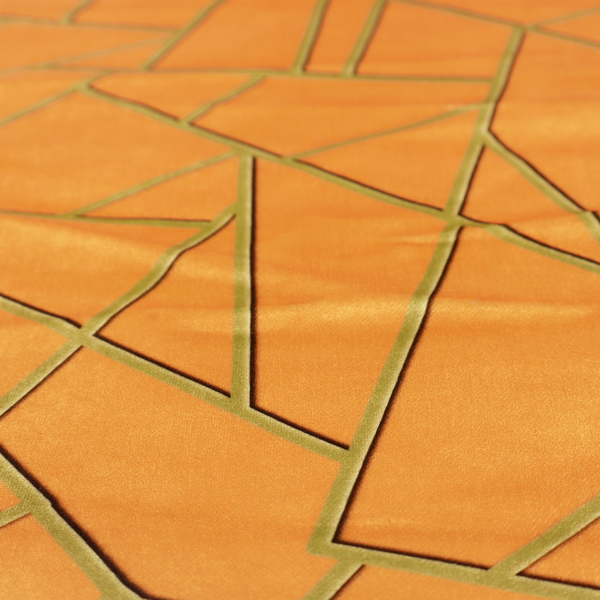 A close-up of a luxurious bright orange or apricot fabric featuring a fractured, geometric mosaic pattern. The warm, vibrant background is segmented by a network of recessed metallic gold lines that form sharp, irregular polygons. This "shattered-glass" effect pairs a bold, citrus-toned base with shimmering, Art Deco-inspired gold linework, creating a high-contrast and architectural look with a subtle 3D texture.