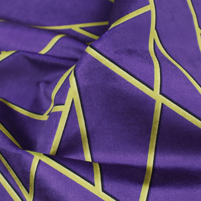 A close-up of a luxurious deep purple or violet fabric featuring a fractured, geometric mosaic pattern. The dark, matte background is segmented by a network of recessed metallic gold lines that form sharp, irregular polygons. This "shattered-glass" effect creates a dramatic visual contrast, blending the rich, royal tones of the textile with shimmering, Art Deco-inspired gold accents for a bold and sophisticated look.
